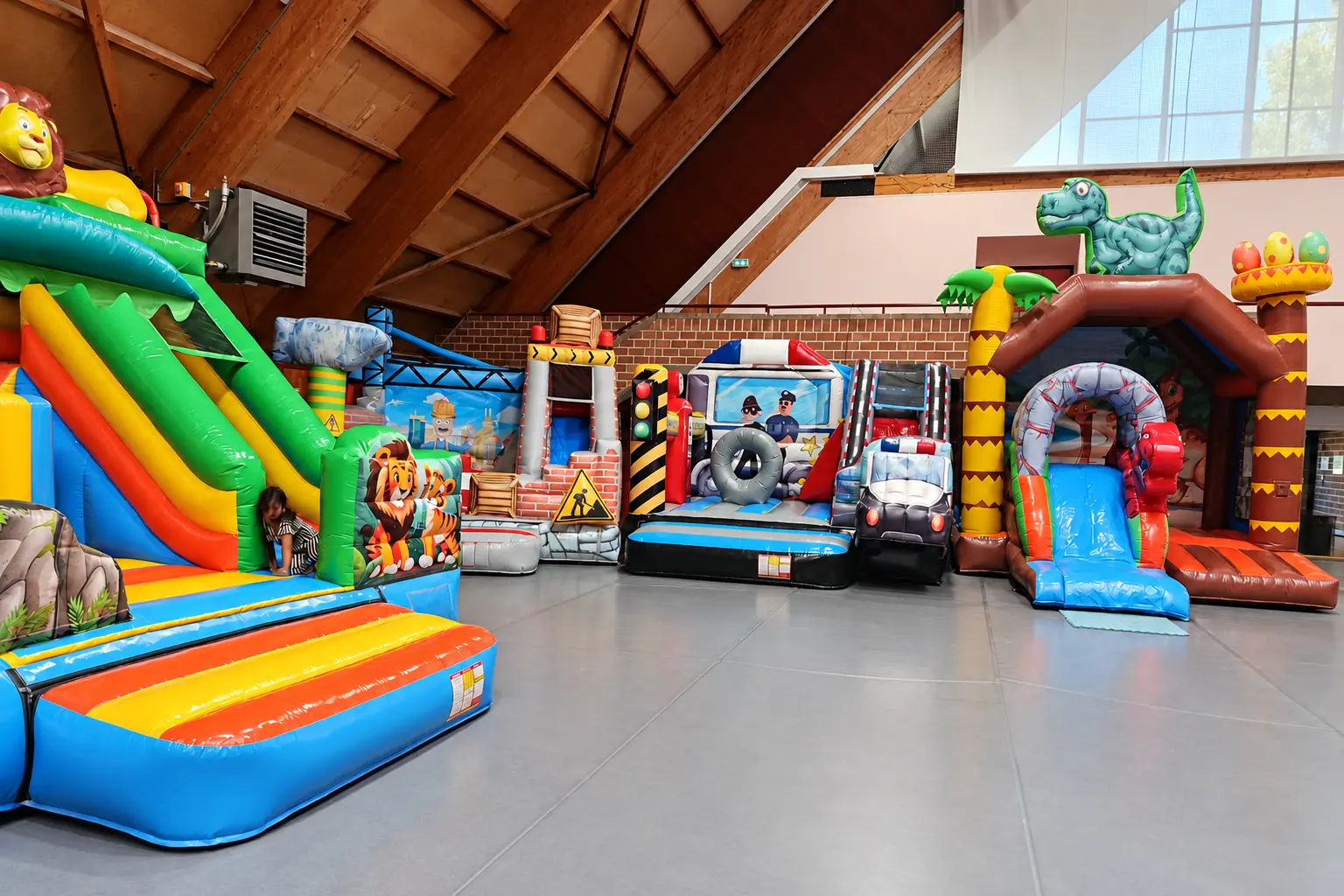 Des structures gonflables alignées dans une salle de sport, un toboggan au premier plan