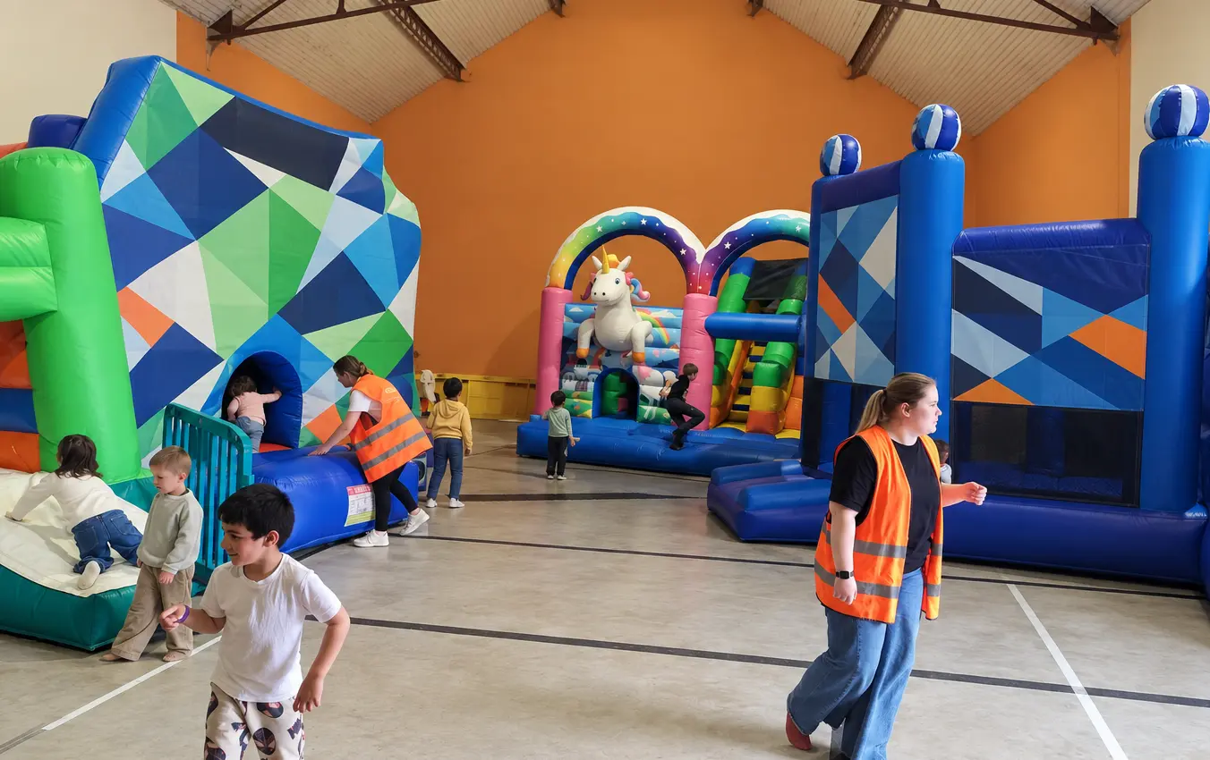 Des enfants jouent entre les structures gonflables, dont une licorne et un toboggan