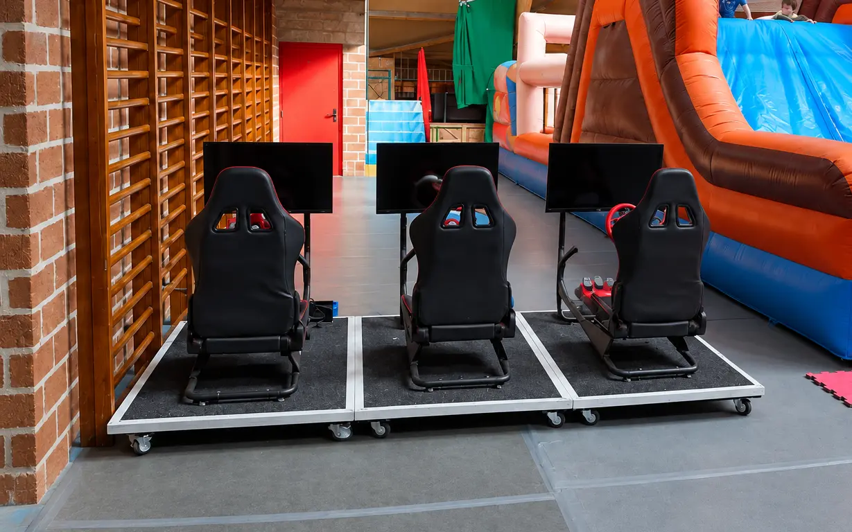 Trois simulateurs de course à côté d'un grand toboggan gonflable